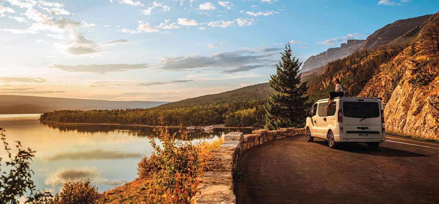 Van aménagé PIlote le long de la route avec une personne sur assise sur le toit.